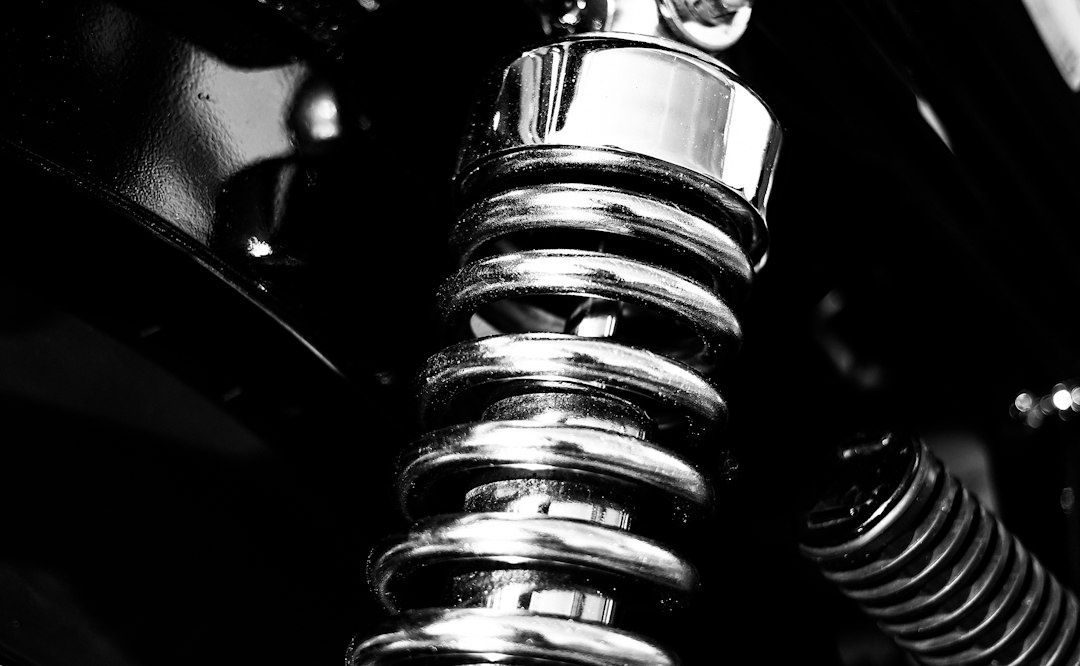 Närbild av en motorcykels blanka bakre stötdämpare med spiralfjäder
